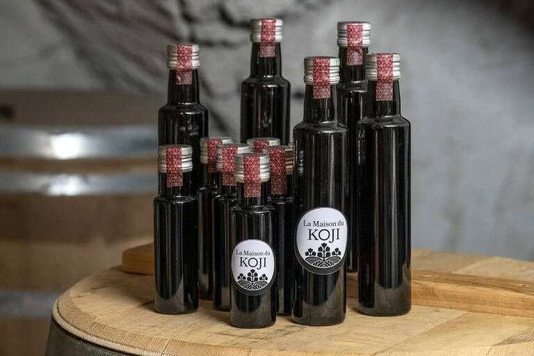 A group of bottles of wine sitting on a wooden barrel.