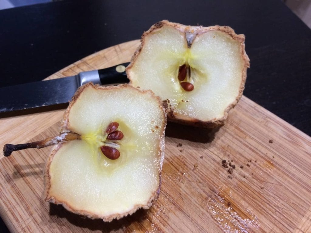 Two pears cut in half with a knife on a cutting board.